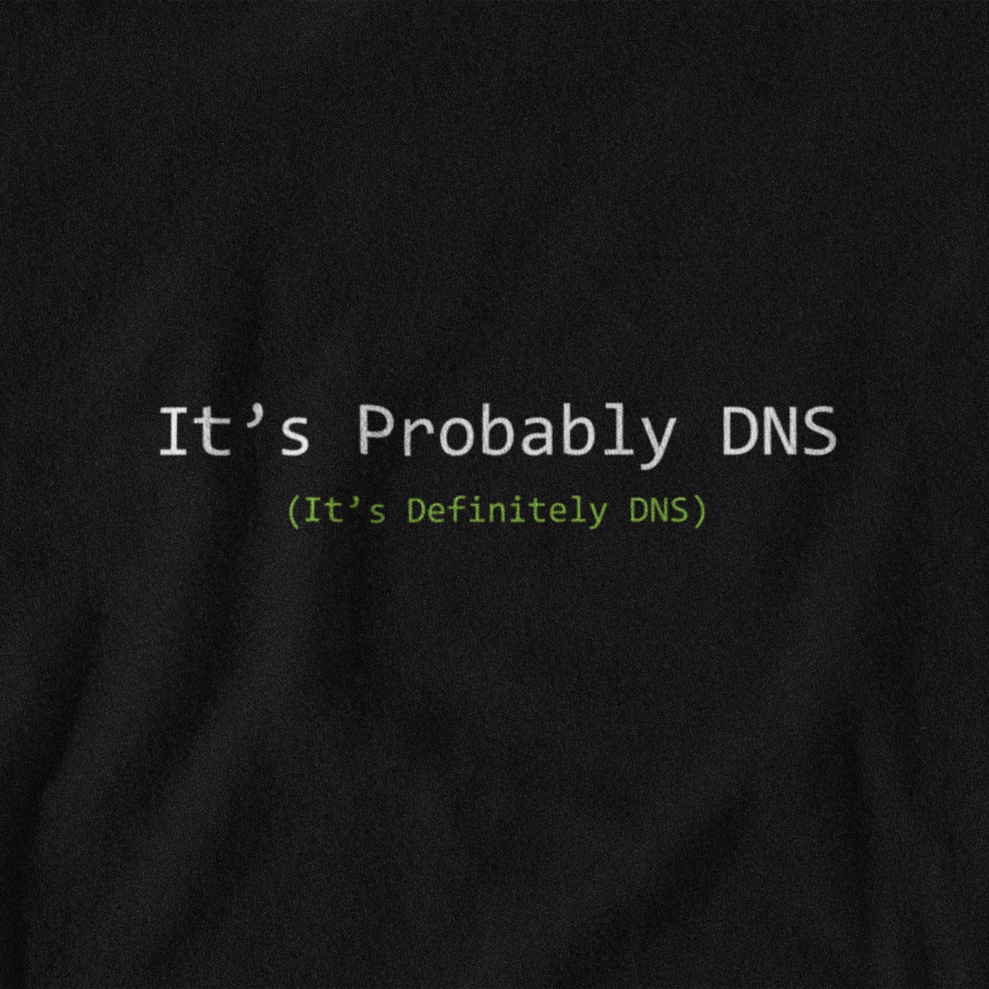 Black t-shirt with text 'It's Probably DNS (It's Definitely DNS)' on a plain background